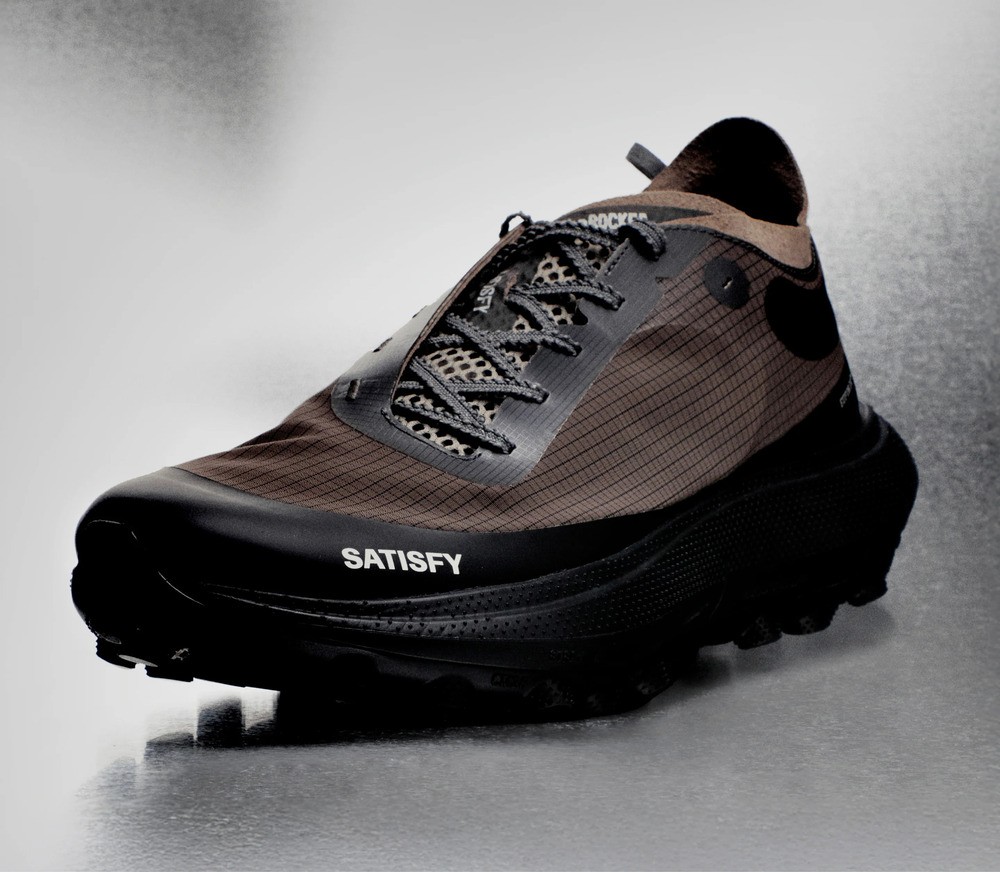 image : theROCKER de Satisfy, une paire de trail running marron vue de trois quart, avec le laçage qui part sur le coté.
